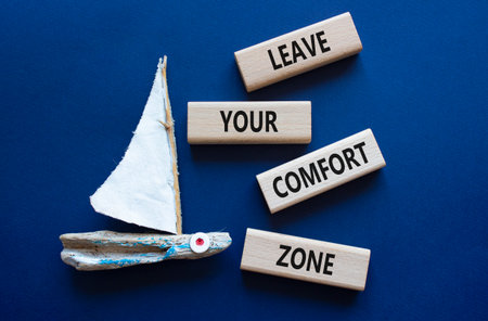 Comfort Zone symbol. Wooden blocks with words Leave your Comfort Zone. Beautiful deep blue background with boat. Business concept. Copy space.の写真素材