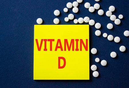 Vitamin D symbol. Concept word Vitamin D on yellow note. Beautiful deep blue background with pills. Medicine and Vitamin D concept. Copy spaceの写真素材