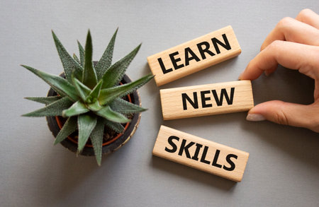 Learn new skills symbol. Concept words Learn new skills on wooden blocks. Beautiful gray background with succulent plant. Businessman hand. Business and Learn new skills concept. Copy space.の写真素材