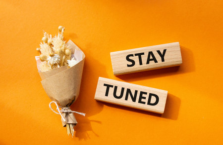 Stay Tuned symbol. Wooden blocks with words Stay Tuned. Beautiful orange background. Business and...