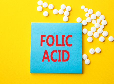 Folic acid symbol. Concept word Folic acid on blue note. Beautiful yellow background with pills. Medicine and Folic acid concept. Copy spaceの写真素材