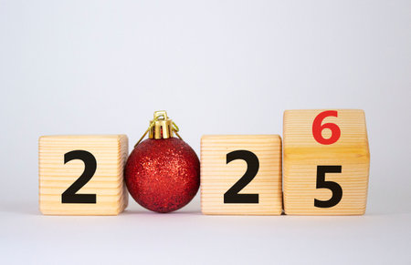 2026 New Year symbol. Businessman turns wooden cube and changes Year 2025 to 2026. Beautiful white background with Christmas ball. Copy space. Business and 2026 new year conceptの写真素材