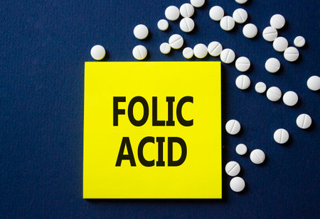 Folic acid symbol. Concept word Folic acid on yellow note. Beautiful deep blue background with pills. Medicine and Folic acid concept. Copy spaceの写真素材