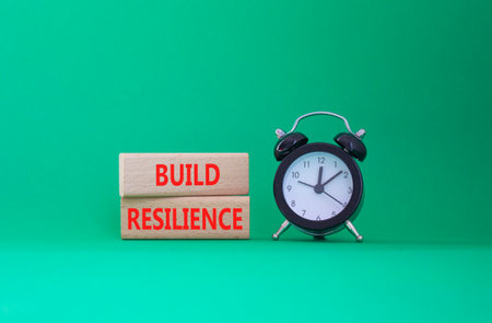 Build resilience symbol. Wooden blocks with words Build resilience. Beautiful green background with alarm clock. Business and Build resilience concept. Copy space.の写真素材