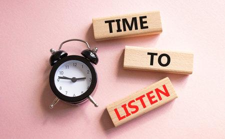 Time to listen symbol. Concept words Time to listen on wooden blocks. Beautiful pink background with...