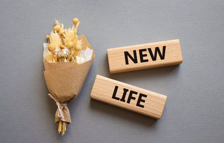 New life symbol. Concept word New life on wooden blocks. Beautiful gray background with bouquet of flowers. Business and New life concept. Copy spaceの写真素材