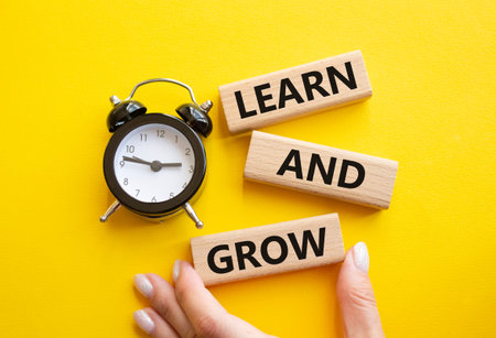 Learn and grow symbol. Concept words Learn and grow on wooden blocks. Businessman hand. Beautiful...