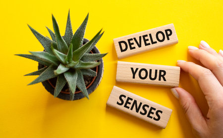 Sense symbol. Wooden blocks with words Develop your Senses. Beautiful yellow background with...