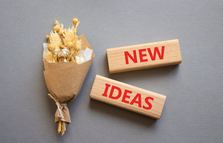 New ideas symbol. Concept word New ideas on wooden blocks. Beautiful gray background with bouquet of flowers. Business and New ideas concept. Copy spaceの写真素材