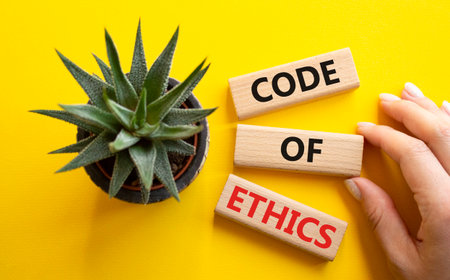 Code of ethics symbol. Concept words Code of ethics on wooden blocks. Businessman hand. Beautiful yellow background with succulent plant. Business and Code of ethics concept. Copy space.の写真素材