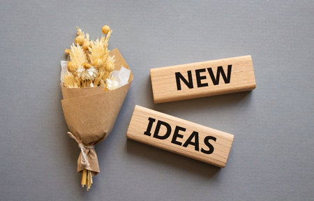 New ideas symbol. Concept word New ideas on wooden blocks. Beautiful gray background with bouquet of flowers. Business and New ideas concept. Copy spaceの写真素材