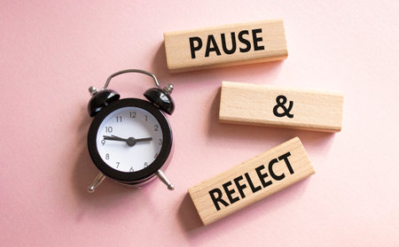 Pause and Reflect symbol. Concept words Pause and Reflect on wooden blocks. Beautiful pink background with alarm clock. Business and Pause and Reflect concept. Copy space.の写真素材