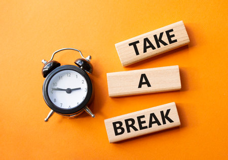 Take a break symbol. Concept words Take a break on wooden blocks. Beautiful orange background with alarm clock. Business and Take a break concept. Copy space.の写真素材