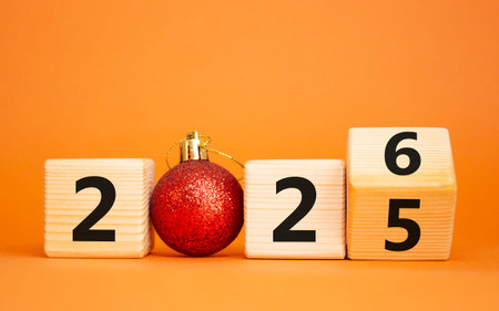 2026 New Year symbol. Businessman turns wooden cube and changes Year 2025 to 2026. Beautiful orange background with Christmas ball. Copy space. Business and 2026 new year conceptの写真素材