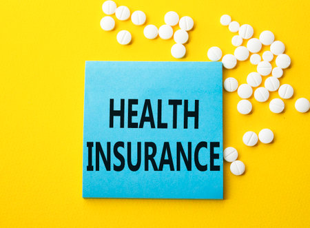 Health Insurance symbol. Concept word Health Insurance on blue note. Beautiful yellow background with pills. Medicine and Health Insurance concept. Copy spaceの写真素材