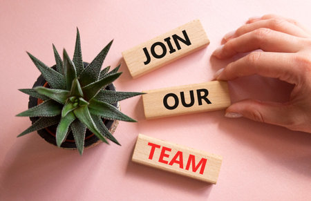 Join our team symbol. Wooden blocks with words Join our team. Beautiful pink background with succulent plant. Businessman hand. Business and Join our team concept. Copy space.の写真素材