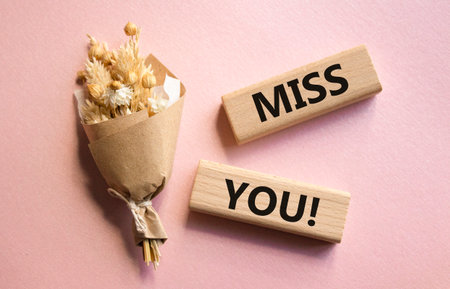 Miss you symbol. Concept word Miss you on wooden blocks. Beautiful pink background with bouquet of flowers. Business and Miss you concept. Copy spaceの写真素材