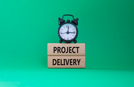 Project Delivery symbol. Concept word Project Delivery on wooden blocks. Beautiful green background with alarm clock. Business and Project Delivery concept. Copy spaceの写真素材