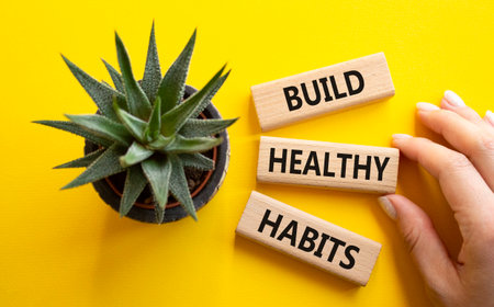 Healthy habits symbol. Concept word Build Healthy habits on wooden blocks. Doctor hand. Beautiful yellow background with succulent plant. Healthy lifestyle and Healthy habits concept. Copy spaceの写真素材