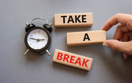 Take a break symbol. Concept words Take a break on wooden blocks. Businessman hand. Beautiful gray background with alarm clock. Business and Take a break concept. Copy space.の写真素材
