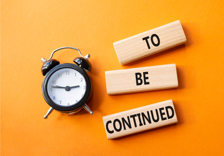 To be continued symbol. Concept words To be continued on wooden blocks. Beautiful orange background with alarm clock. Business concept and To be continued. Copy space.の写真素材