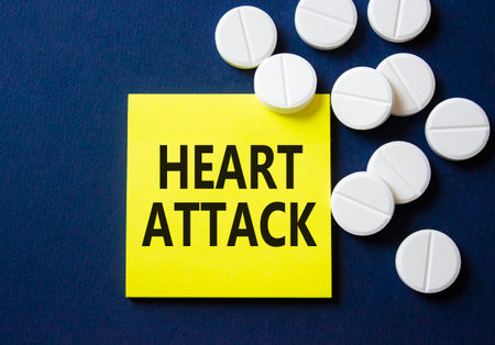 Heart Attack symbol. Concept word Heart Attack on yellow note. Beautiful deep blue background with pills. Medicine and Heart Attack concept. Copy spaceの写真素材