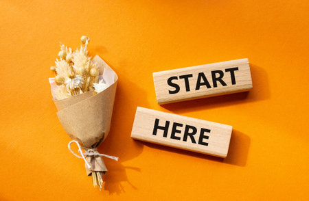 Start here symbol. Wooden blocks with words Start here. Beautiful orange background. Business and Start here concept. Copy space.の写真素材