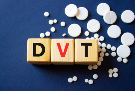 DVT symbol. Wooden cubes with words DVT Deep vein thrombosis. Beautiful deep blue background. Healthcare and Deep vein thrombosis concept. Copy space.の写真素材