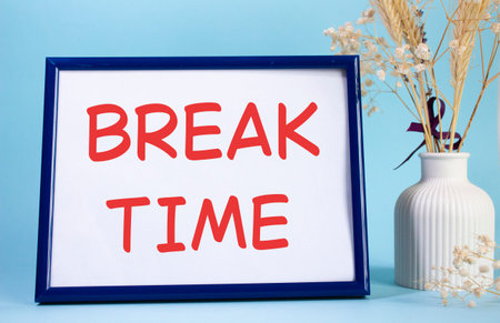 Break Time symbol. Concept words Break Time on beautiful wooden picture frame. Beautiful light blue background with flower vase. Business and Break Time concept. Copy space.の写真素材