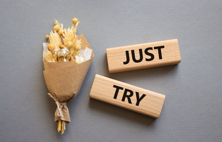 Just try symbol. Concept words Just try on wooden blocks. Beautiful gray background with bouquet of flowers. Business and Just Try concept. Copy space.の写真素材