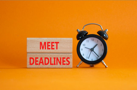 Meet Deadlines symbol. Concept word Meet Deadlines on wooden blocks. Beautiful orange background with alarm clock. Business and Meet Deadlines concept. Copy spaceの写真素材
