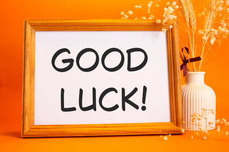Good luck symbol. Concept words Good luck on beautiful wooden picture frame. Beautiful orange background with flower vase. Business and Good luck concept. Copy space.の写真素材