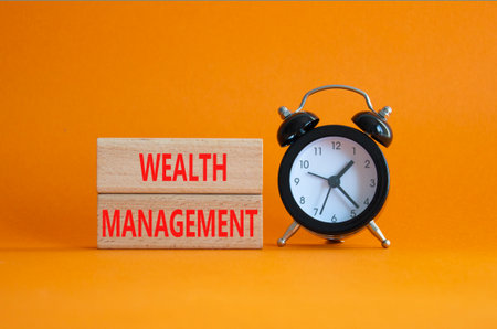 Wealth Management symbol. Concept words Wealth Management on wooden blocks. Beautiful orange background with alarm clock. Business and Wealth Management concept. Copy spaceの写真素材