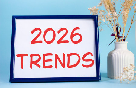 2026 Trends symbol. Concept words 2026 Trends on beautiful wooden picture frame. Beautiful light blue background with flower vase. Business and 2026 Trends concept. Copy space.の写真素材
