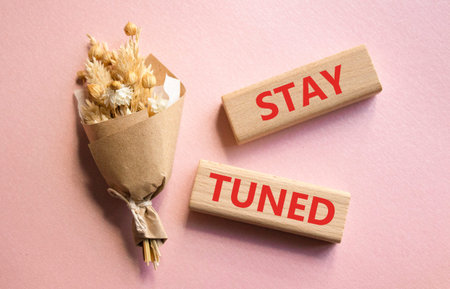 Stay Tuned symbol. Wooden blocks with words Stay Tuned. Beautiful pink background. Business and Stay...