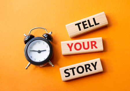 Tell your story symbol. Wooden blocks with words Tell your story. Beautiful orange background with alarm clock. Business and Tell your story concept. Copy space.の写真素材