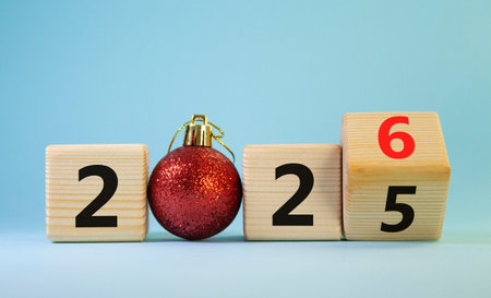 2026 New Year symbol. Businessman turns wooden cube and changes Year 2025 to 2026. Beautiful light...