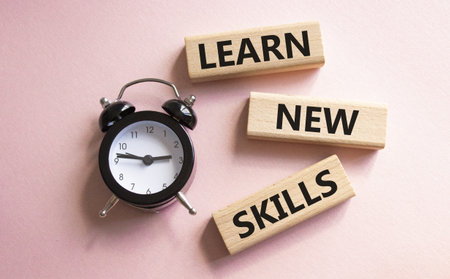 Learn new skills symbol. Concept words Learn new skills on wooden blocks. Beautiful pink background with alarm clock. Business and Learn new skills concept. Copy space.の写真素材