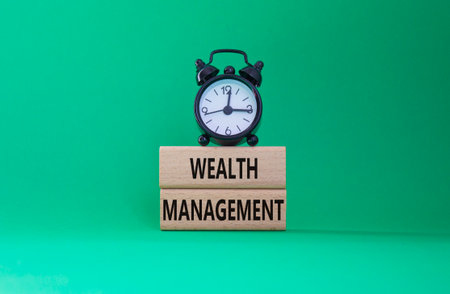 Wealth Management symbol. Concept words Wealth Management on wooden blocks. Beautiful green background with alarm clock. Business and Wealth Management concept. Copy spaceの写真素材