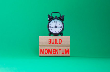 Build momentum symbol. Wooden blocks with words Build momentum. Beautiful green background with...