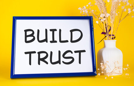 Build trust symbol. Concept words Build trust on beautiful wooden picture frame. Beautiful yellow...