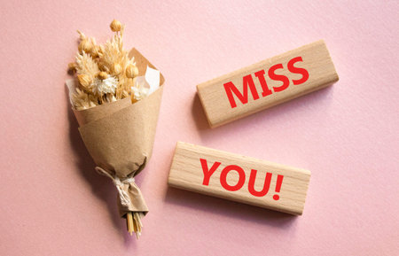 Miss you symbol. Concept word Miss you on wooden blocks. Beautiful pink background with bouquet of flowers. Business and Miss you concept. Copy spaceの写真素材