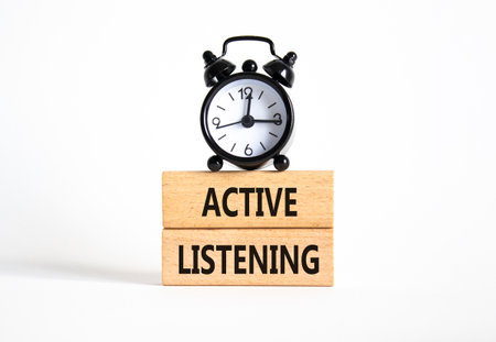 Listen actively symbol. Wooden blocks with words Listen actively. Beautiful white background with alarm clock. Business and Active listening concept. Copy space.の写真素材