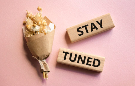 Stay Tuned symbol. Wooden blocks with words Stay Tuned. Beautiful pink background. Business and Stay Tuned concept. Copy space.の写真素材