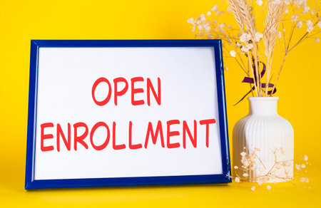 Open Enrollment symbol. Concept words Open Enrollment on wooden picture frame. Yellow background with flower vase. Business and Open Enrollment concept. Copy space.の写真素材