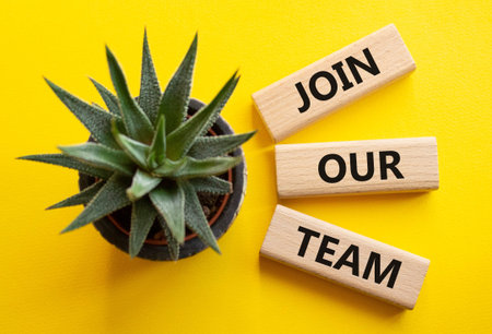 Join our team symbol. Wooden blocks with words Join our team. Beautiful yellow background with...