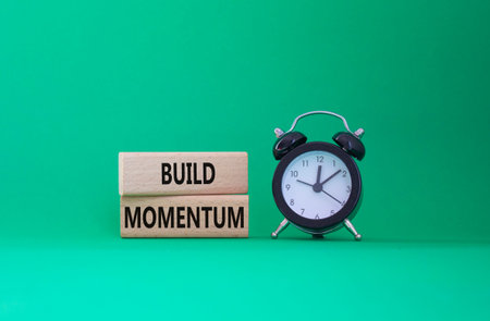 Build momentum symbol. Wooden blocks with words Build momentum. Beautiful green background with...