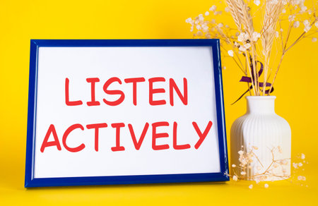 Listen actively symbol. Concept words Listen actively on beautiful wooden picture frame. Beautiful yellow background with flower vase. Business and Listen actively concept. Copy space.の写真素材