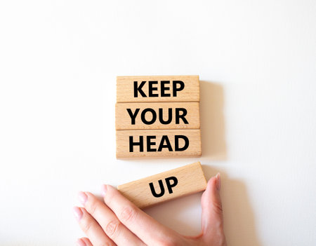 Keep Your Head Up symbol. Concept words Keep Your Head Up on wooden blocks. Beautiful bright white background. Businessman hand. Business and Keep Your Head Up concept. Copy space.の写真素材