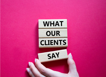 Clients symbol. Concept words What our Clients Say on wooden blocks. Beautiful bright red background. Businessman hand. Business and What our Clients Say concept. Copy space.の写真素材